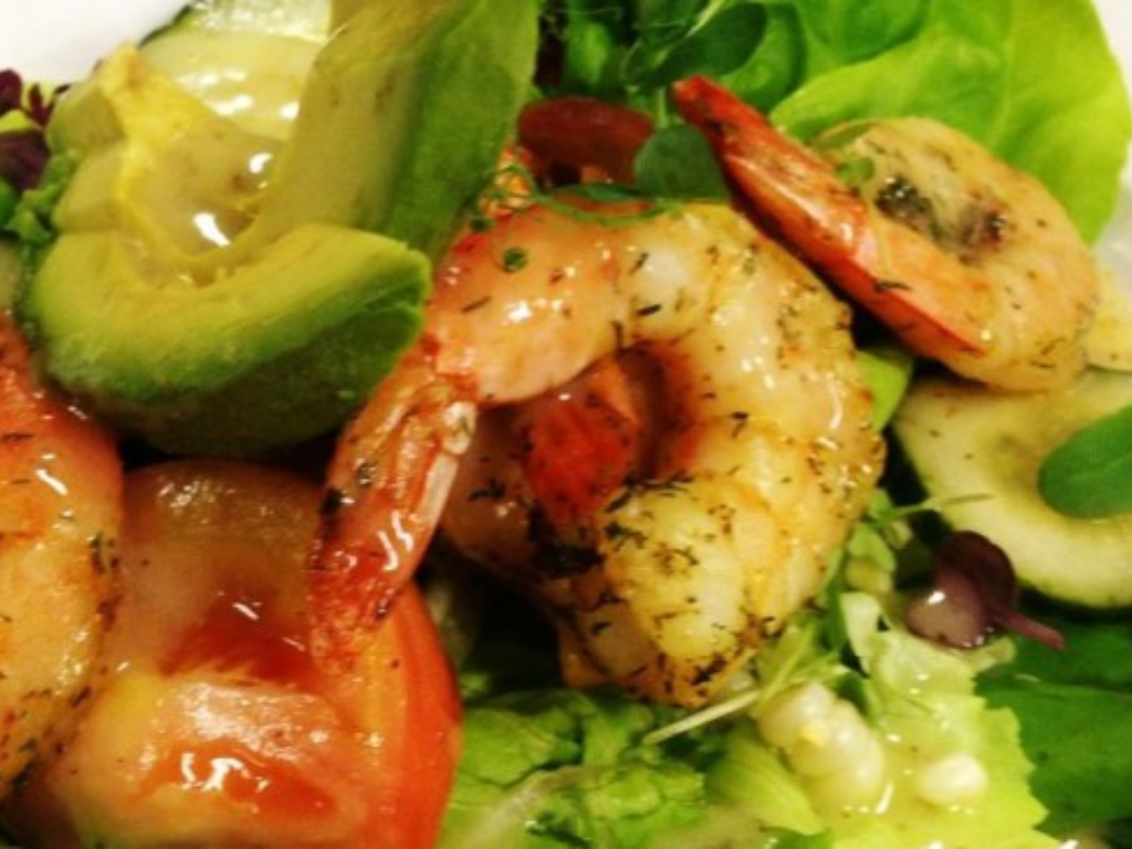 a plate of shrimp salad with lettuce and avocado